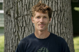 Kevin Bingham stands next to a healthy ash tree in front of his home