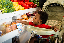 A baby checking out the produce at the Flint Farmers Market.  Image by: Avram Golden