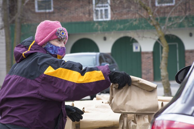 A volunteer distributes sack lunches outside of the Isabella Community Soup Kitchen.
