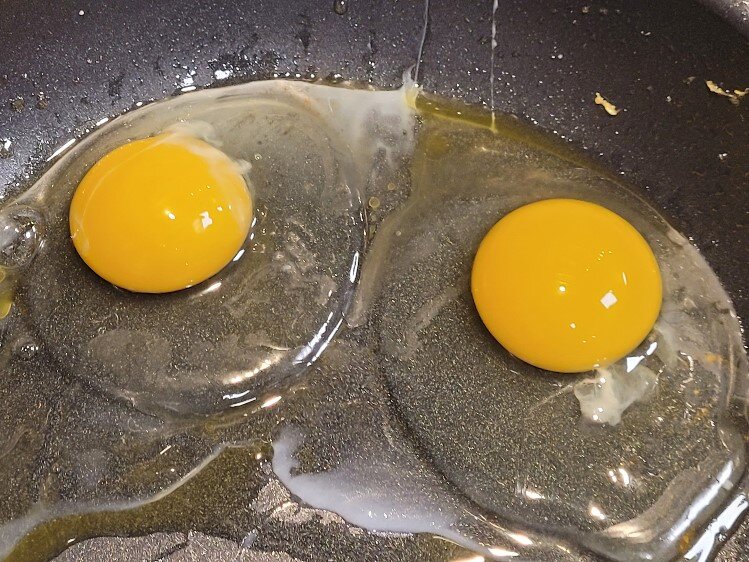Eggs, sunny side up, in the fry pan.