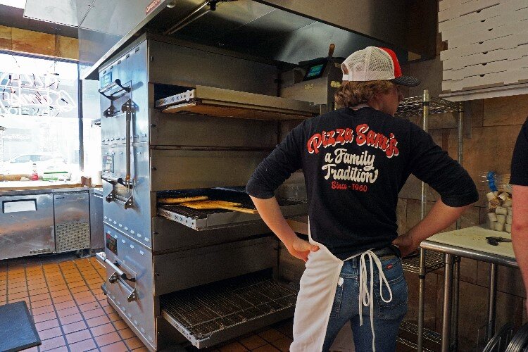 Connor Lijewski waits for a pizza to emerge from the oven so it can be sliced and served as fresh as possible.