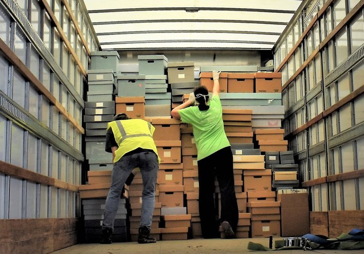 Volunteers stack boxes of documents and materials to move to another location.
