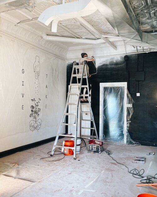 Lyndsay Edmonds, owner of Harless + Hugh Coffee as she paints the cafe with a new coat of white. (PC: Julia Ross/Harless + Hugh)