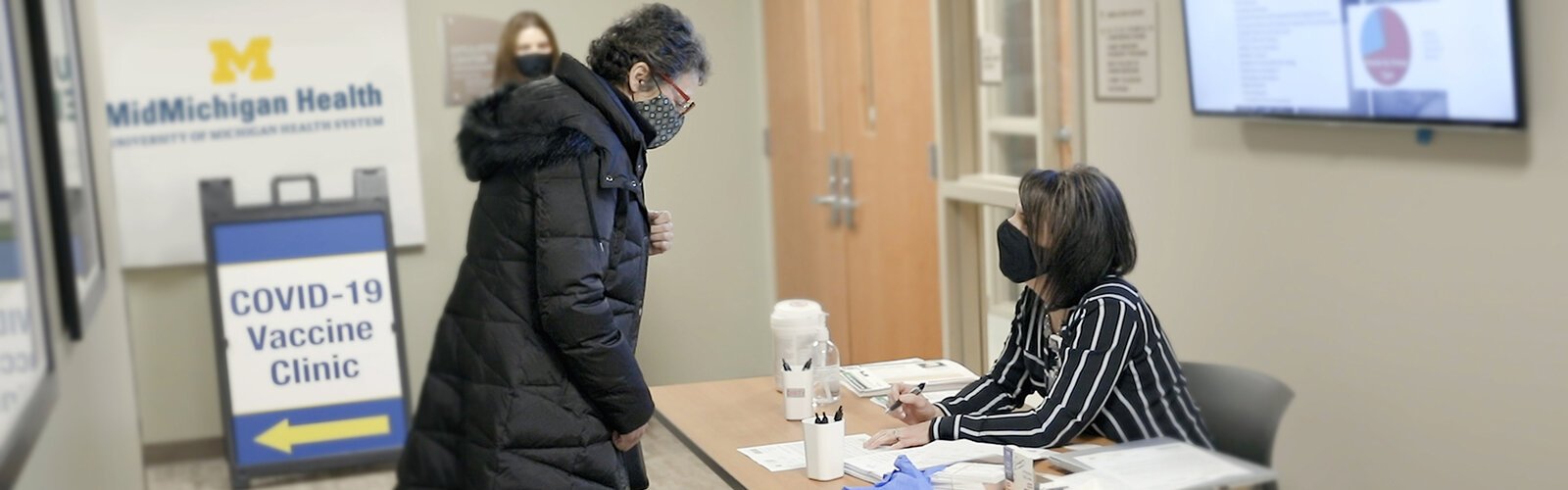 Melanie Kalmar, of Midland, checks in for her COVID-19 vaccine with Melisa McLeod-Blohm, director, MidMichigan Physicians Group, at a recent vaccination clinic.