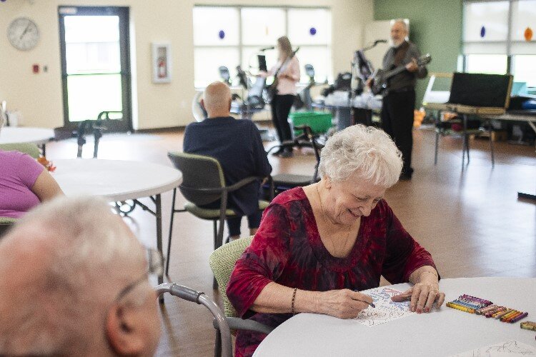 Rachel Gentis, a resident of Pinecrest Farms, fills in a coloring page while listening to a live musical performance.