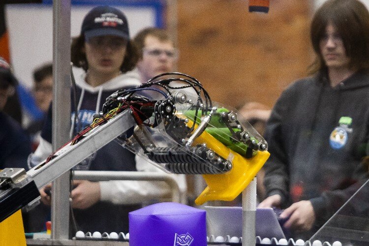 A robot grabs hold of a rubber cone while teams compete in the FIRST.