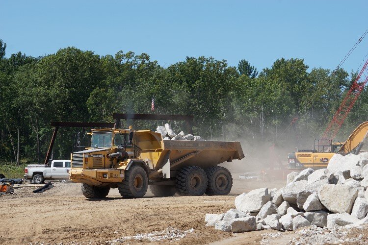 Trucks flow in and out of the site frequently, shuttling rocks, dirt, and other materials.