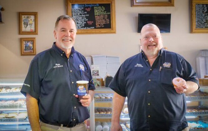 Greg "Ryno" Rynearson, left, and Alan "Bubba" White stand aside the delicious offerings at their beloved Cops & Doughnuts.