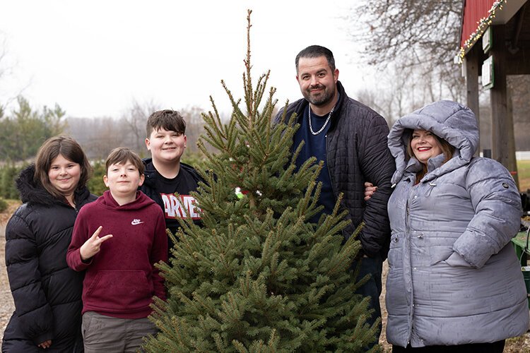 The Tomlinson family poses with their Christmas tree at Shea Tree Farm.