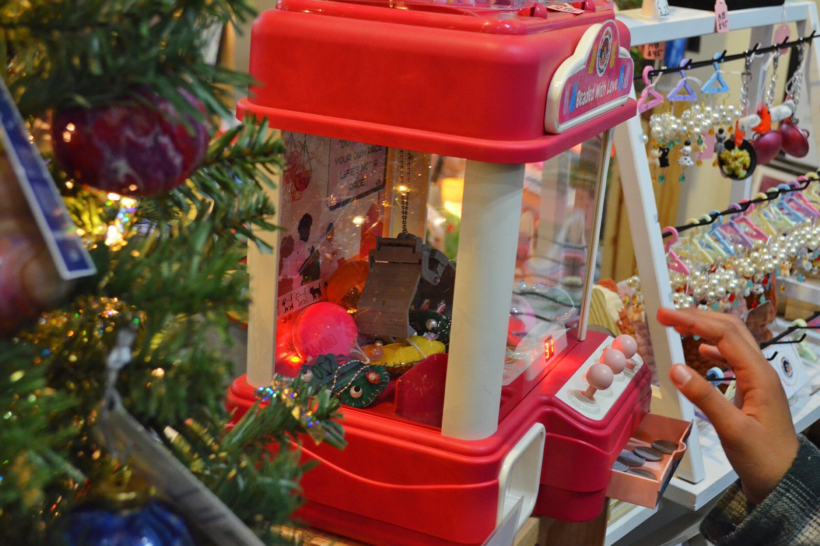 A shopper plays to beat the clock in a lucky claw game that dispenses small plastic containers with products from the winter market. 