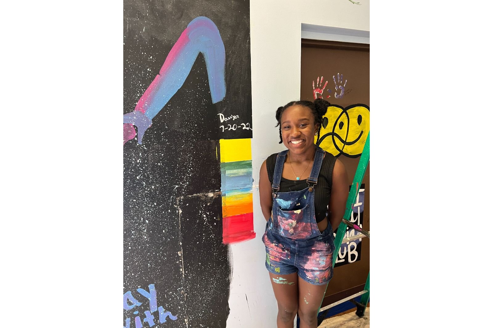 Davia McCoy poses by her mural. 