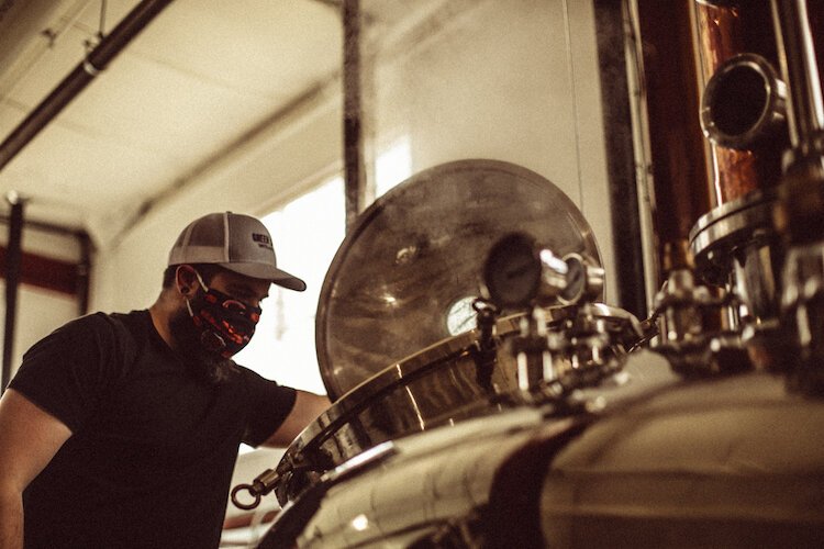 Tyler Glasser, head distiller and production manager, is shown using equipment at Green Door Distilling Co. to produce alcohol-based hand sanitizer.