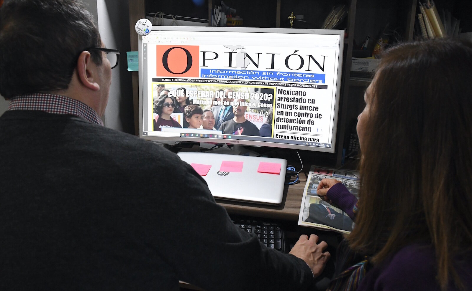 Lucinda Mosquera and Jesus Grillo check pages of their newspaper on a computer.