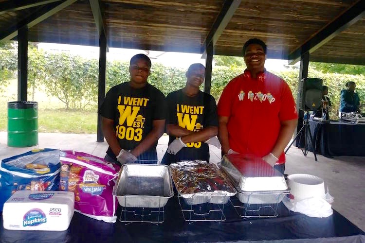 R'Shaun Palmer, in the red T-shirt with two youth participants of the ROYAL summer program serve food at the organizations second annual Back 2 School Jam.