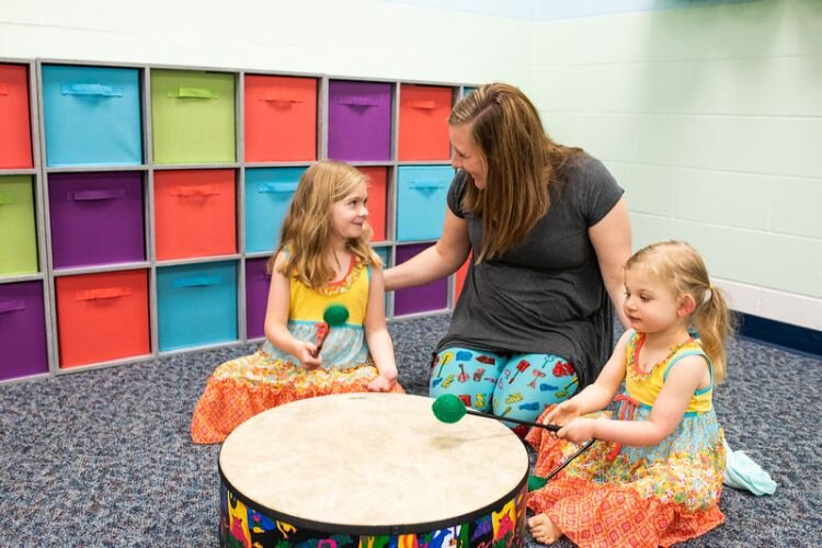 A teacher encourages youngsters with the drum.