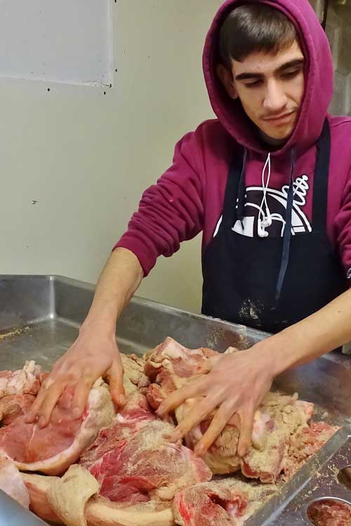 A worker sprinkles spices in the sausage.