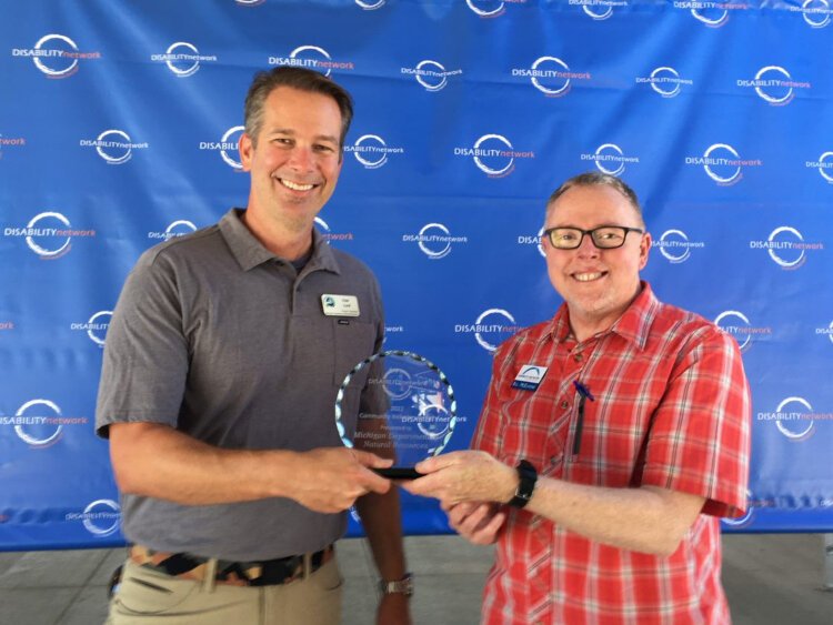 A representative of the Michign Department of Natural Resources stands with Bill McElhone (Disability Network Southwest Michigan board member) after receiving the 2022 Community Inclusion Award.