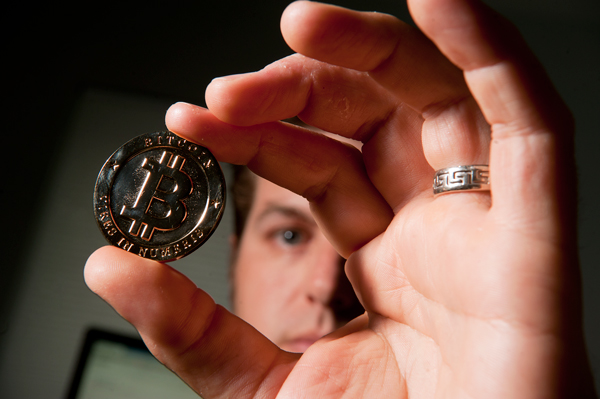 Michael Garyet holds a promo coin for the online currency bitcoin