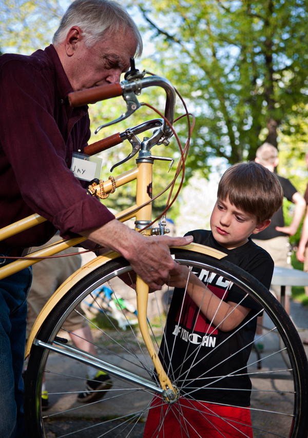 James Balkema, 5, right, tightens a screw on his bike with the help of Open Roads volunteer Jay Baumer.