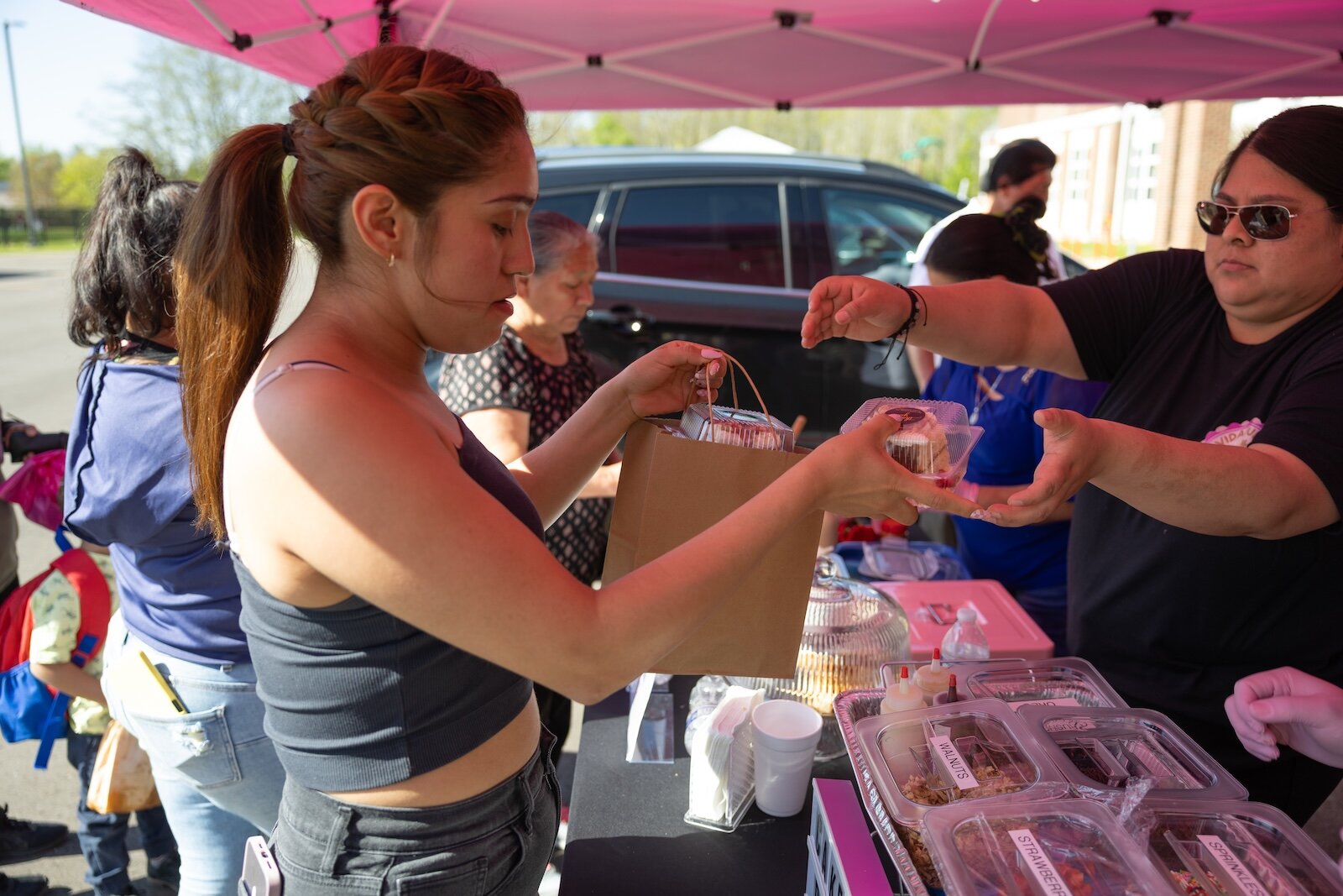 Esperanza Herrera (right) hands off an order of pasteles during El Concilio’s Mercadito de Primavera on May 9, 2025. “I opened Vida Dulce at the end of last October,” she said. With the help of the Camino al Éxito program her business took off.