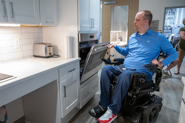 The test kitchen highlights open spaces under the counter and sink for chairs or wheelchairs, lowered ovens, and cabinets with pull-down wire shelving. 