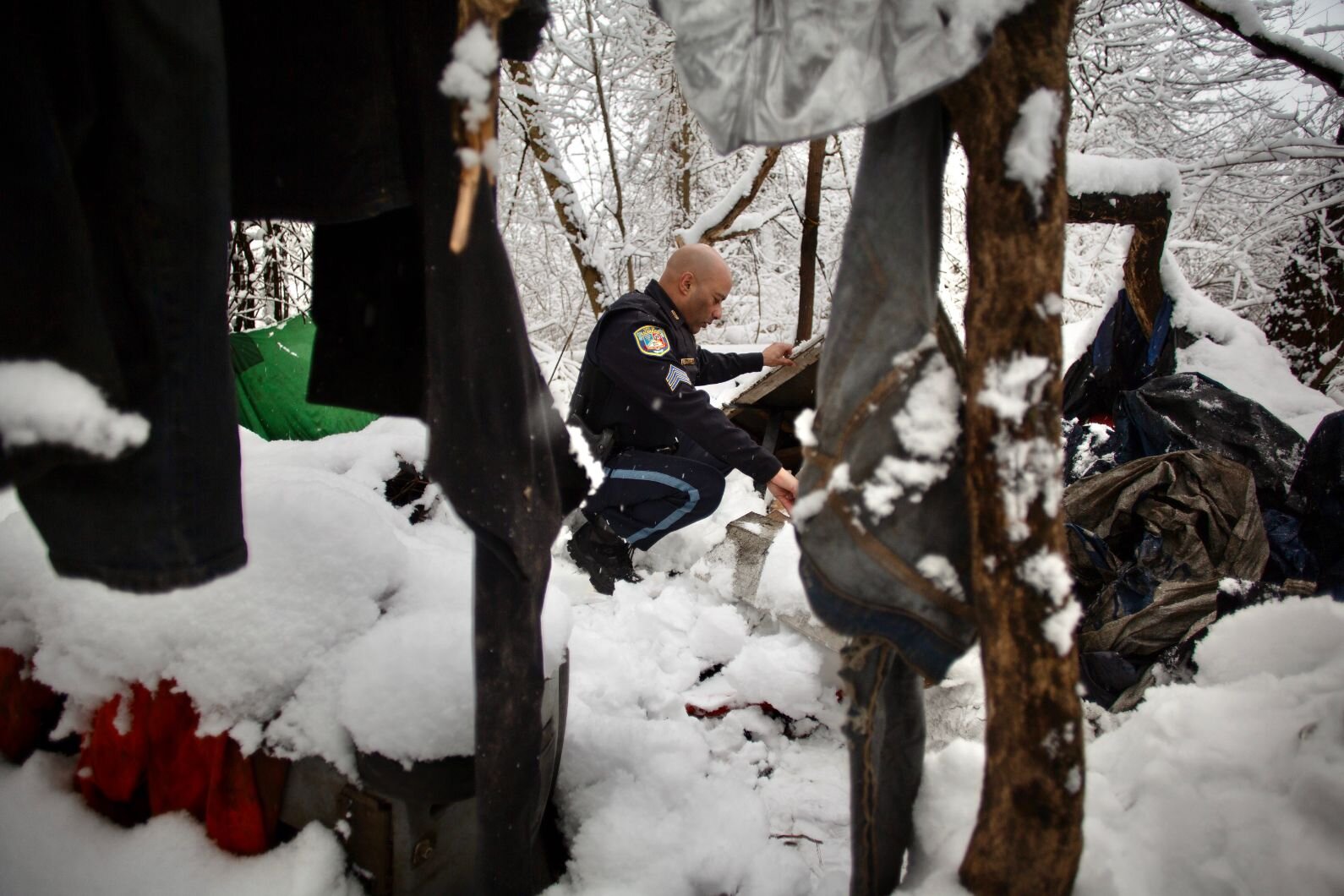 Sgt Amil Alwan of the Kalamazoo Department of Public Safety looks at refuse left at a site where unhoused people camped. He says it is very unsafe for people to camp outdoors in the city.