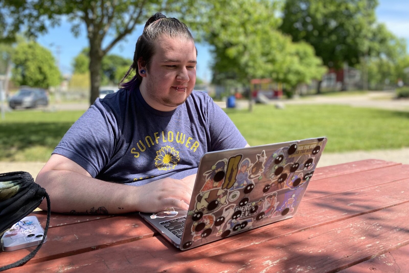 Ashton Smith looks through pictures on his laptop on a Saturday afternoon at Scidmore Park in Three Rivers. He participates in group therapy once a month online, and sees another therapist on a biweekly basis who specializes in gender affirming care