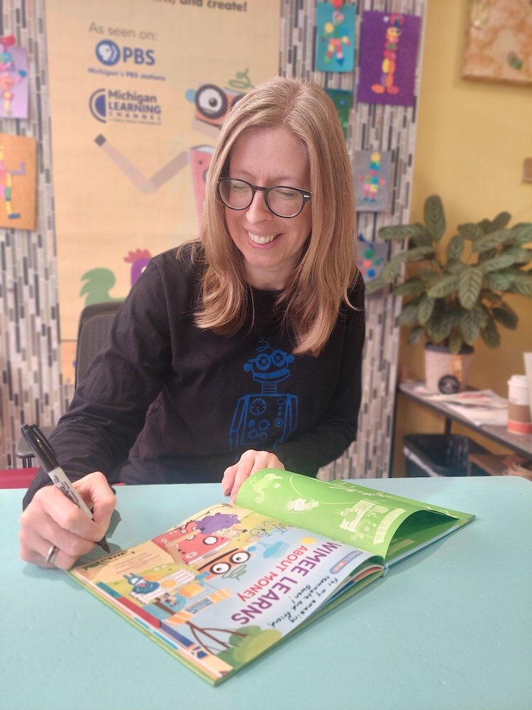 Stephanie Kammeraad, Wimee author, signs a book.