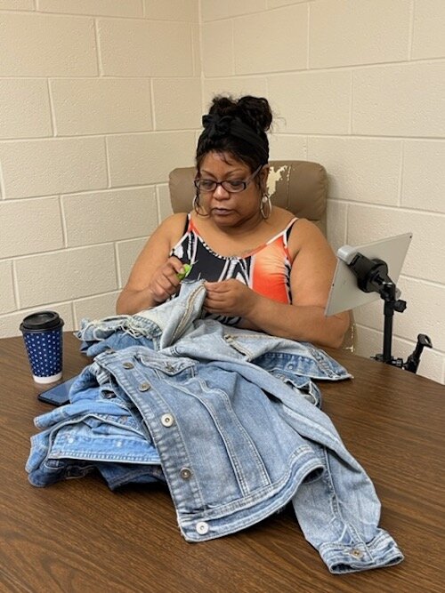 Ayanna Williams, a Sewing Supervisor at the Co-op, holds a denim jacket that she will be embroidering.