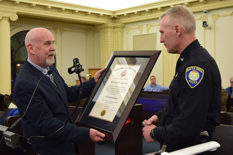 Robert Stevenson, executive director of the MACP and a retired chief, presents the accreditation certificate to Police Chief Jim Blocker. 