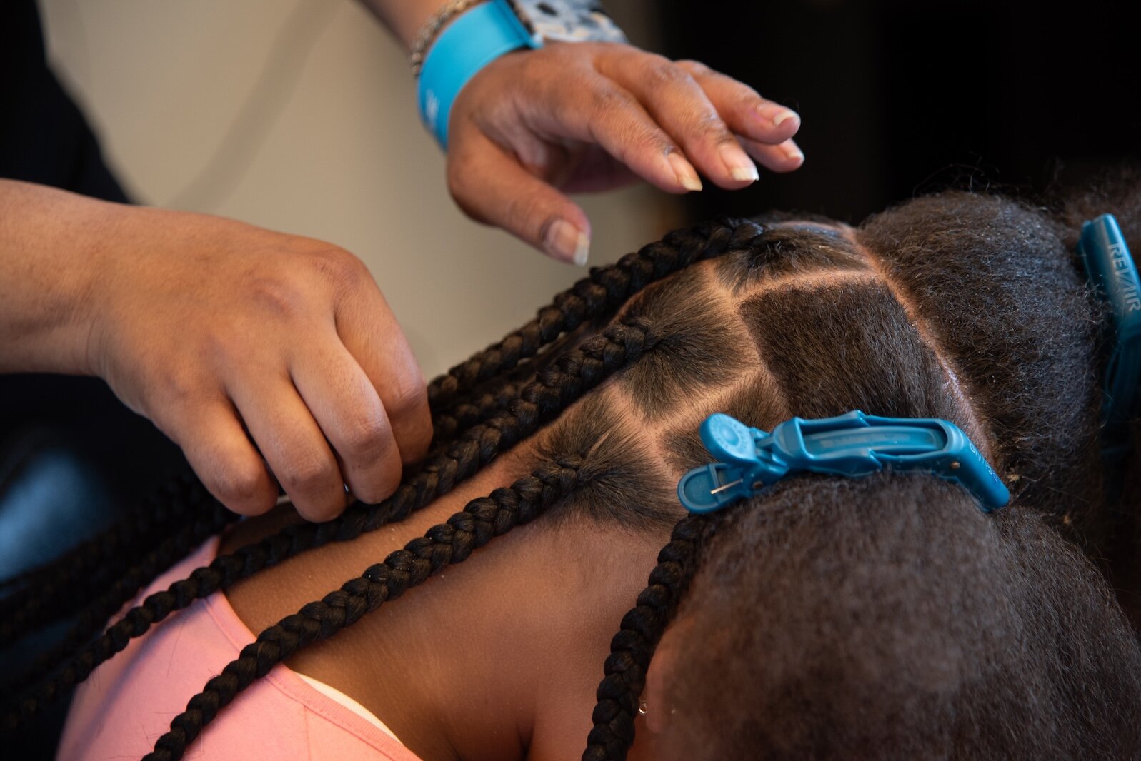 Brianna Cox of Braids by Brie, one of six partner hair professional salons and barbershops that work with Dream of Kalamazoo Foundation, at work braiding hair.  