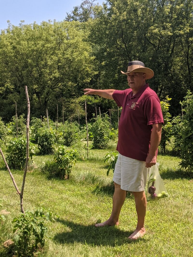 Carlos Fontana points out the various plants he has growing in his farm garden.