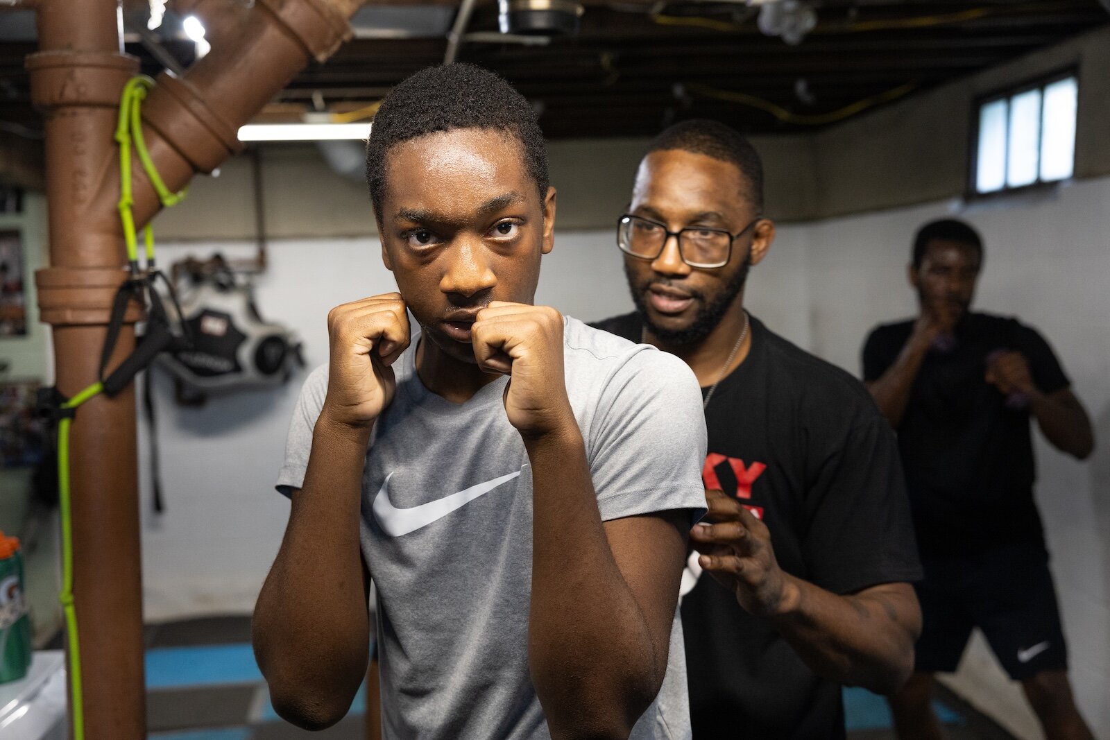 Aimua Osuki, 13, right, trains under the steady gaze of Coach Ja, left. Osuki was 6 when his parents emigrated from Nigeria to Lansing, MI. They moved again to Kalamazoo when he was 8. He is one of the newest arrivals at ChampsDen.