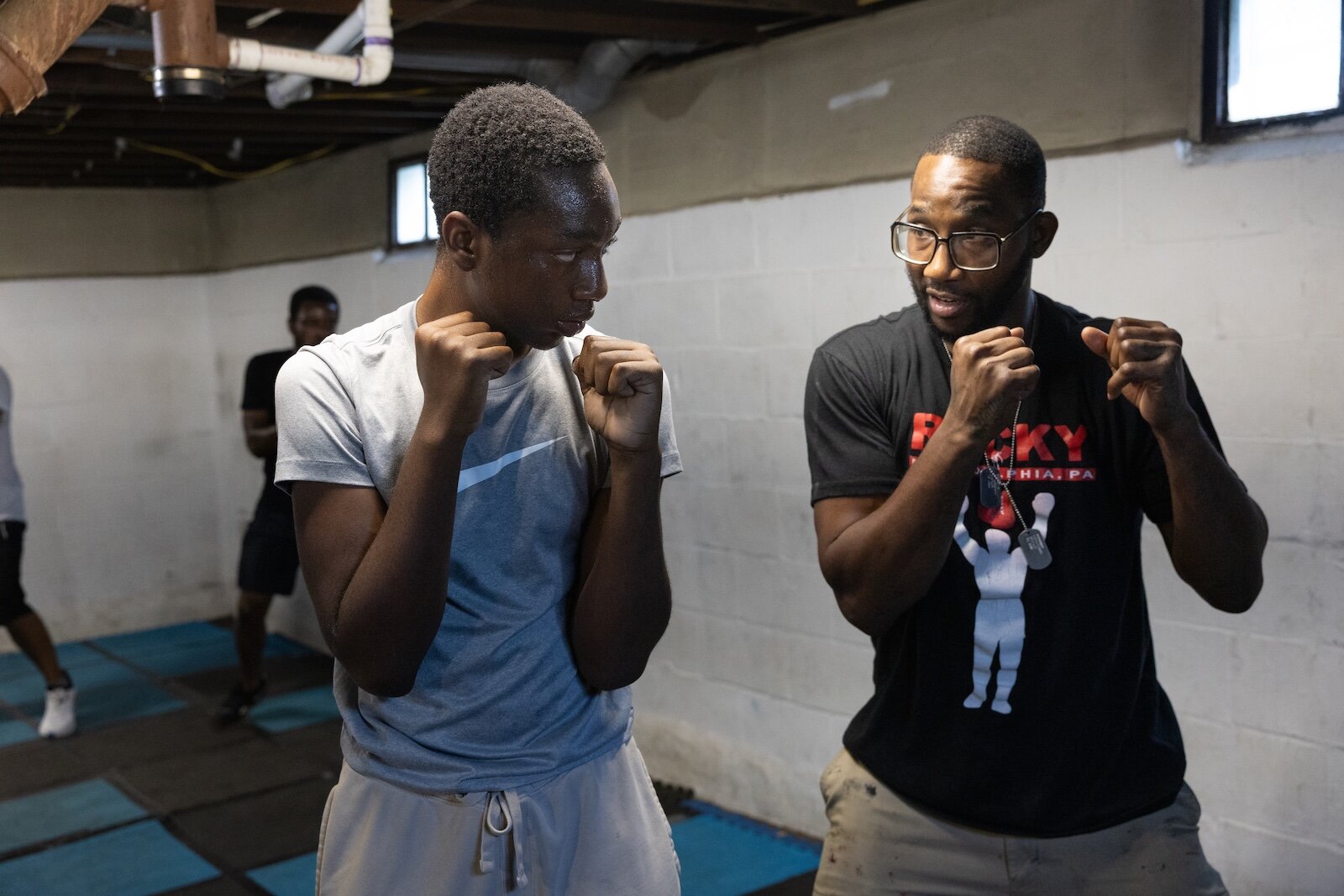 Aimua Osuki, 13, right, trains under the steady gaze of Coach Ja, left. Osuki was 6 when his parents emigrated from Nigeria to Lansing, MI. They moved again to Kalamazoo when he was 8. He is one of the newest arrivals at ChampsDen.