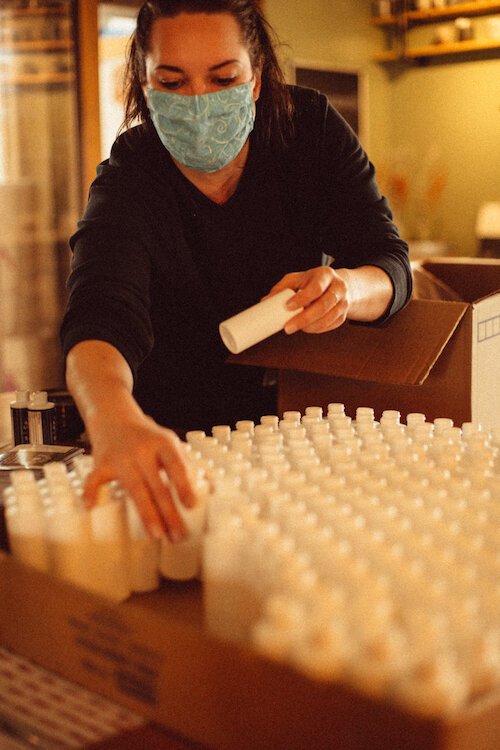 Chelsea Stephens, tasting room manager and events manager for Green door Distilling Co., is shown arranging bottles for hand sanitizer. Since the distillery pivoted in late March, she has also been its hand sanitizer manager.