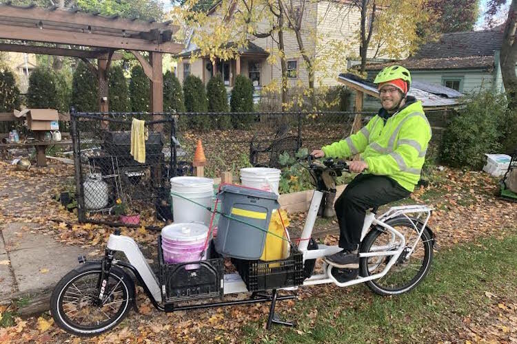 Chris Broadbent Is shown on a bicycle he uses to collect solid food waste for composting. The collection route for his year-old business requires him to pedal anywhere from five to 14 miles per day.