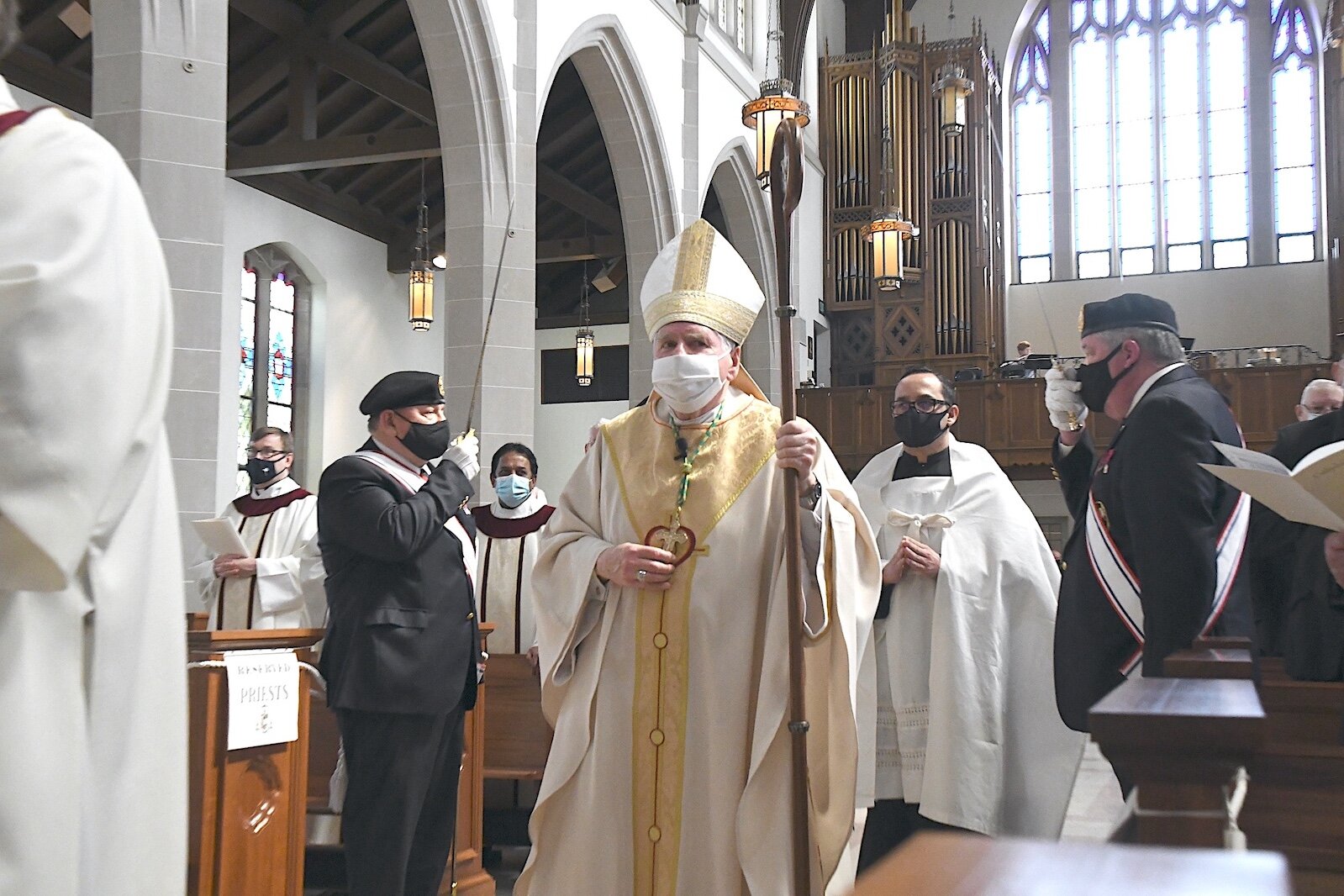 Bishop Paul Bradley of the Catholic Diocese of Kalamazoo, wearing protective gear, processes into St. Augustine Cathedral last year.