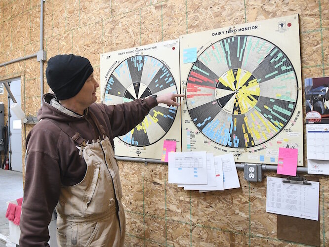 Brad Crandall points to a dairy herd monitoring system, in addition to the computer-based he uses.