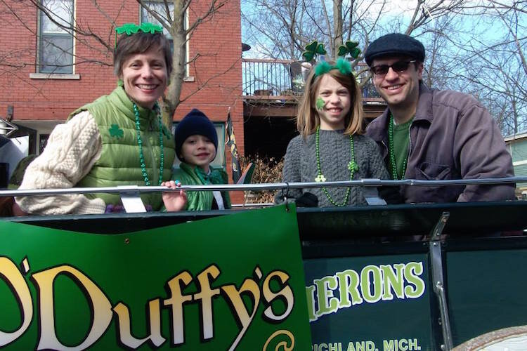 Each year O'Duffy's Pub sponsors a St. Patrick's Day float. Here Vine Neighborhood Association Director, his wife Sarah Drumm, and their two children ride along.