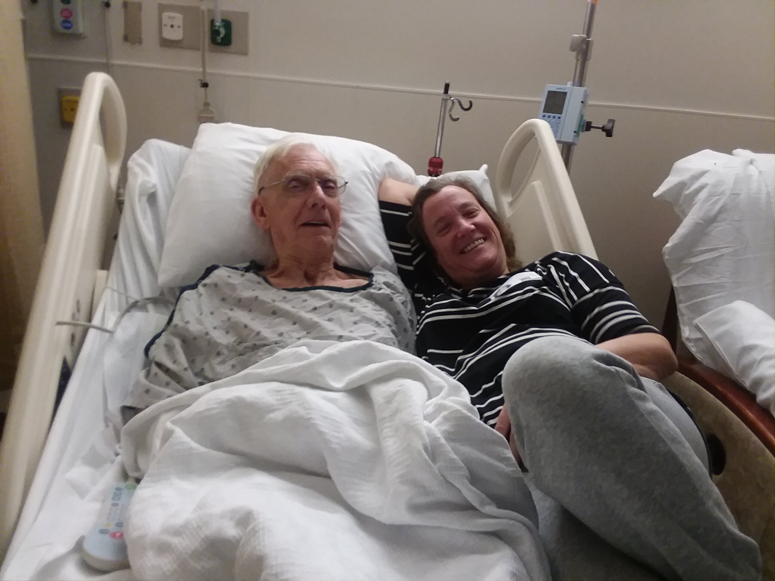 Darcy Thiel, right, lays in a hospital bed with her father, David Thiel during one of his hospitalizations before his death in 2018 of complications from Parkinson's disease.