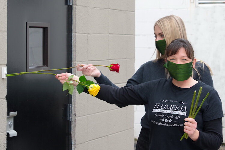 Elisha Hodge and an employee wear masks made out of leaves and use rose stems to ring a doorbell prior to the state-madated closure of non-essentail businesses.