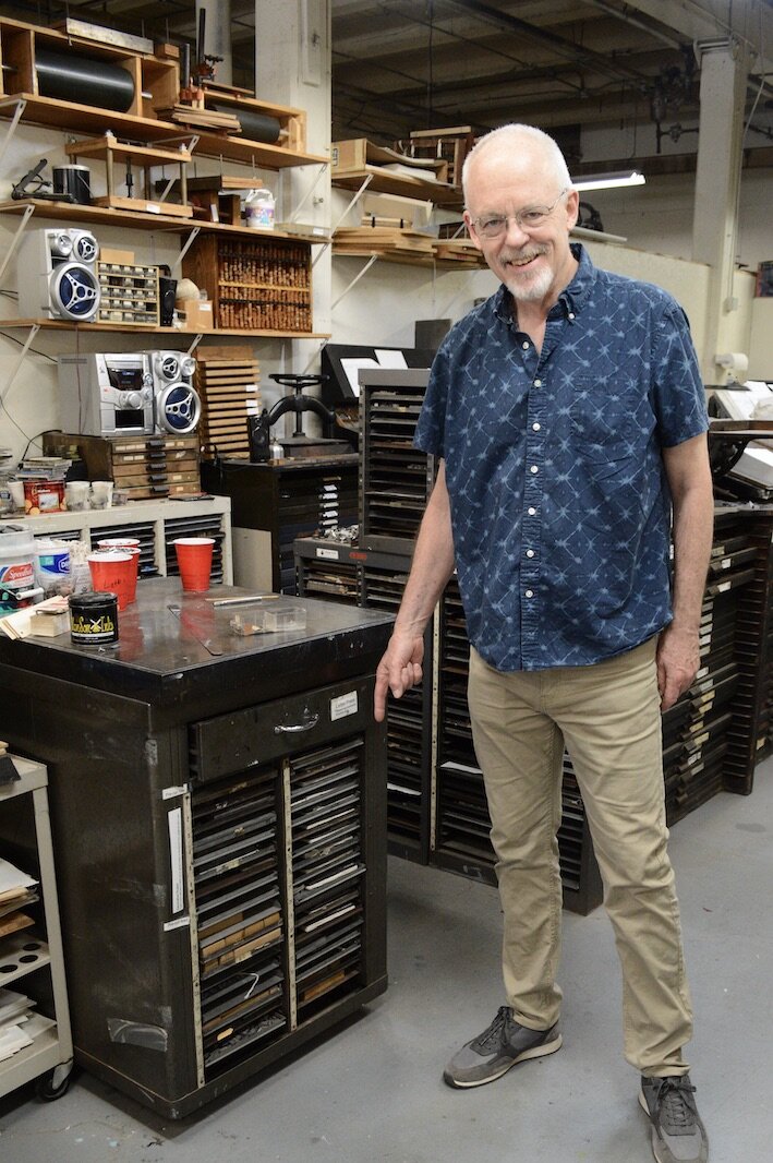 Kalamazoo Book Arts Center executive director Jeff Abshear points to cabinet of type laid out for the letterpress of "Truth Comes Slowly.”