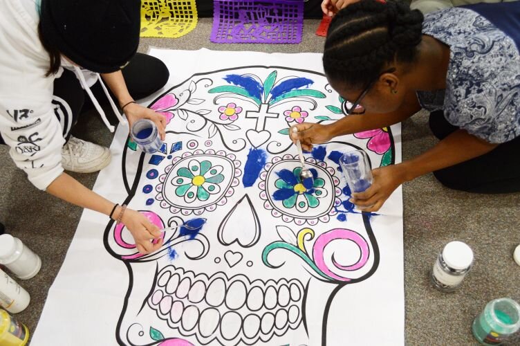 WMU Spanish department teaching assistants decorate a calavera poster.