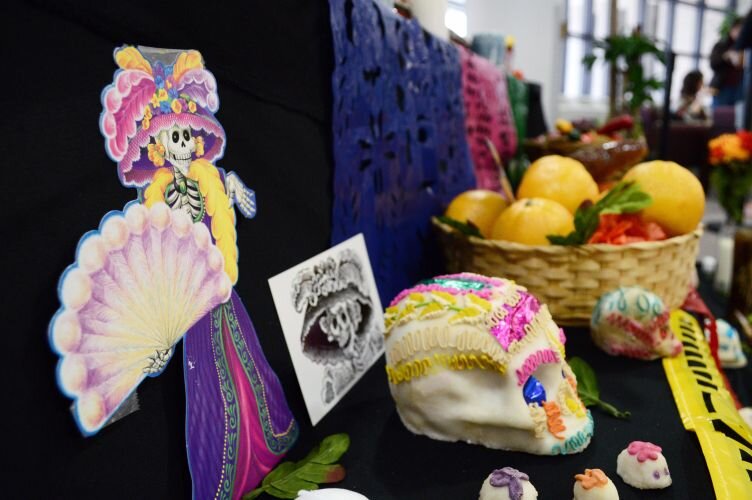 Images of Catrinas, sugar skulls, baskets of fruit on display.