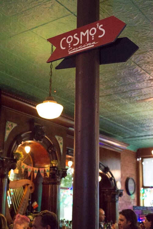 This sign points the way to Cosmo's Cucina, which is up the stairs where a lovely patio sheltered by colorful umbrellas and large trees overlooks the street.