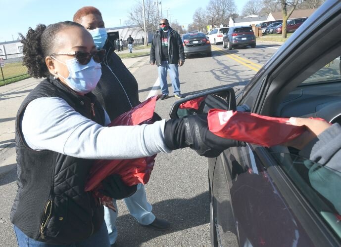 Sonja Dotson hands out a package for children outside New Level Ministries on West Van Buren Street on Saturday morning.