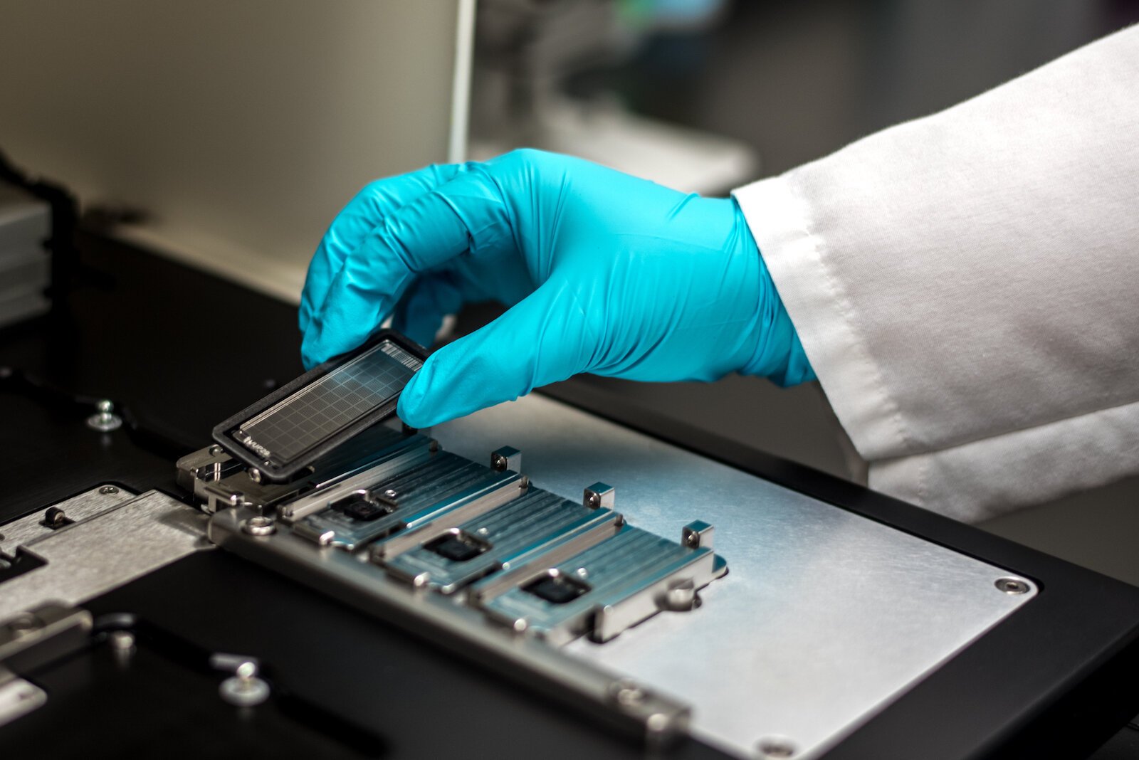 A worker at Genemarkers in Kalamazoo places a tray designed to hold miniscule DNA samples into a machine at the business’s lab.