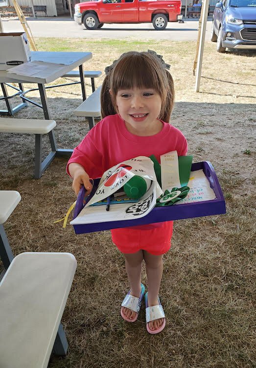 Hadlee Strunk, age 6, poses with a handful of projects she had just gotten done exhibiting at last year’s Calhoun County Fair.