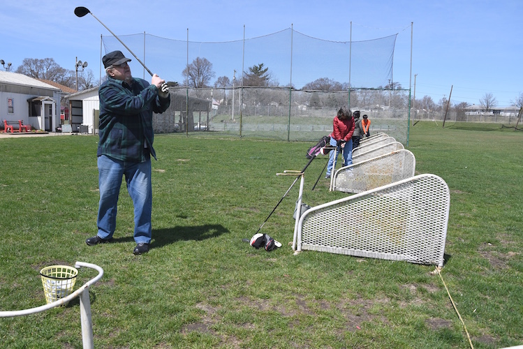 Joe Romo and others hit balls at the driving range.