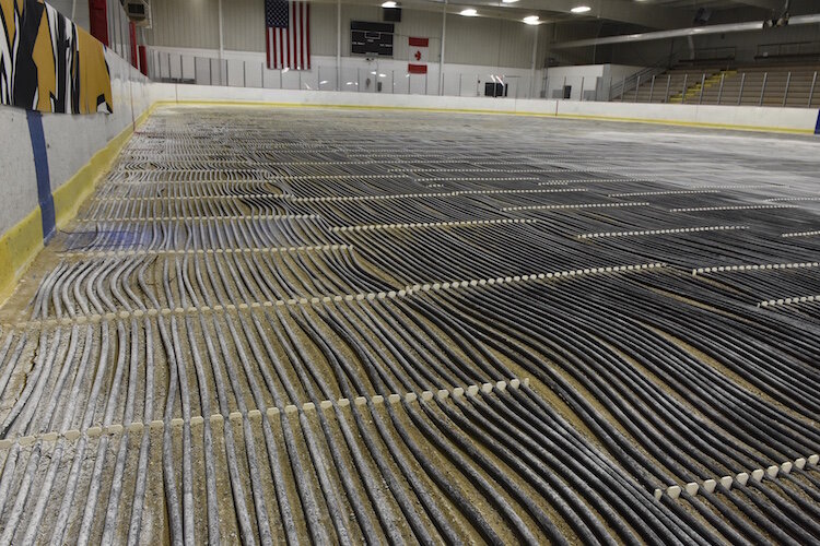 The floor of the hockey rink currently is not covered with ice.